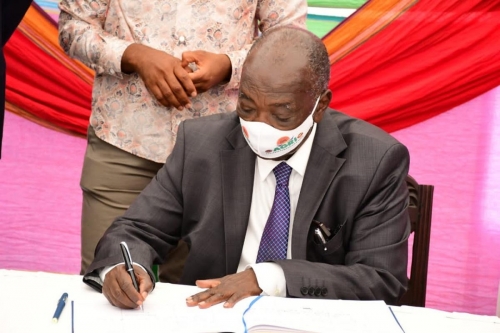 Hon.-Mwebesa-signs-the-visitors-book-at-the-opening-ceremony-of-the-Symposium-on-Wed-8th-Sept-2021.